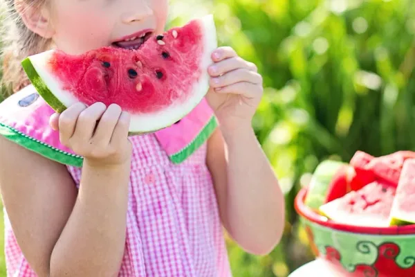 A child eats a healthy snack of watermelon (pixels.com)